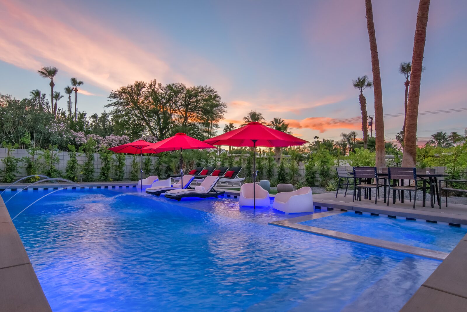 5 Palms Estate pool at sunset with red umbrellas and mountains beyond