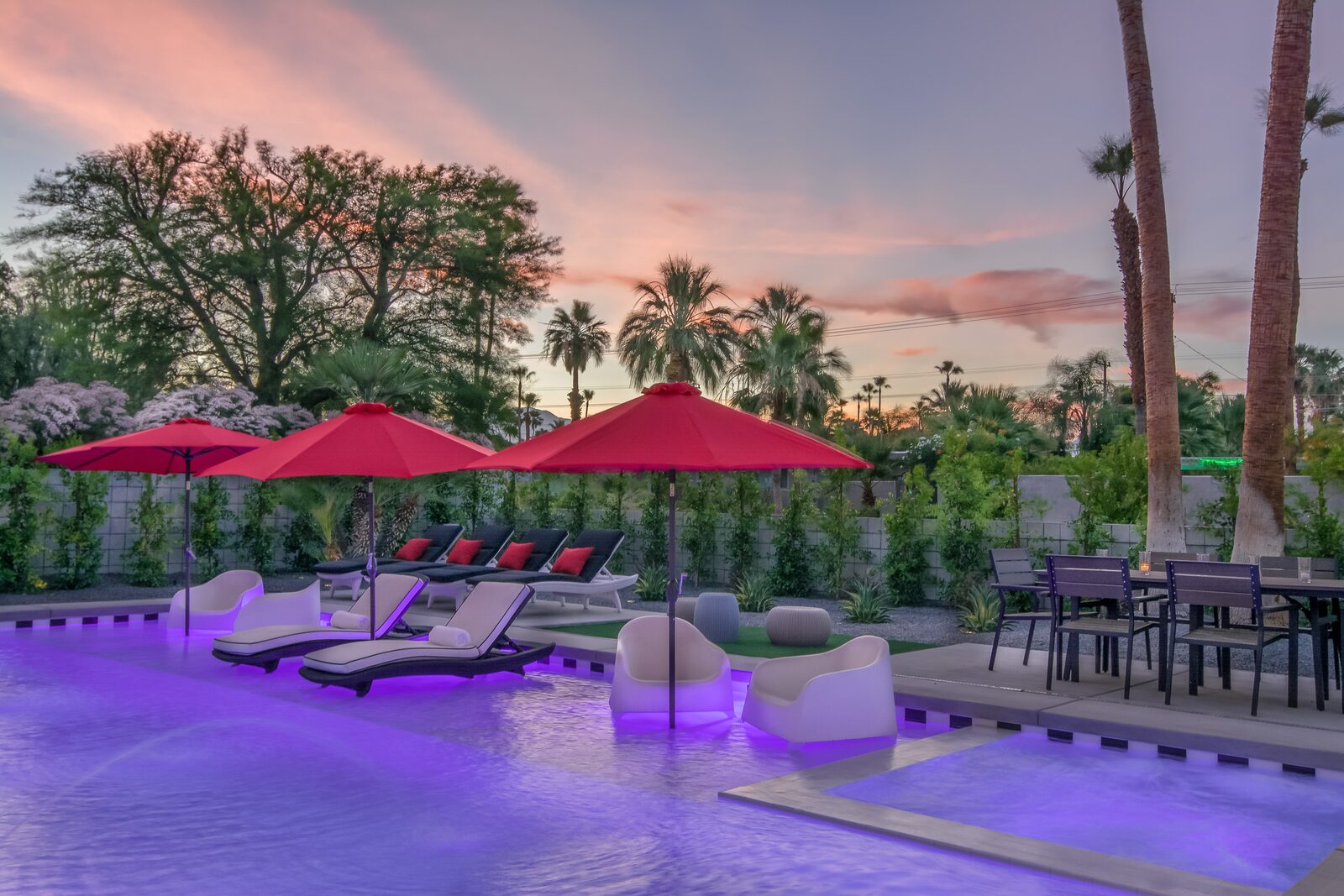 5 Palms Estate outdoor loungers under sunset sky with red umbrellas