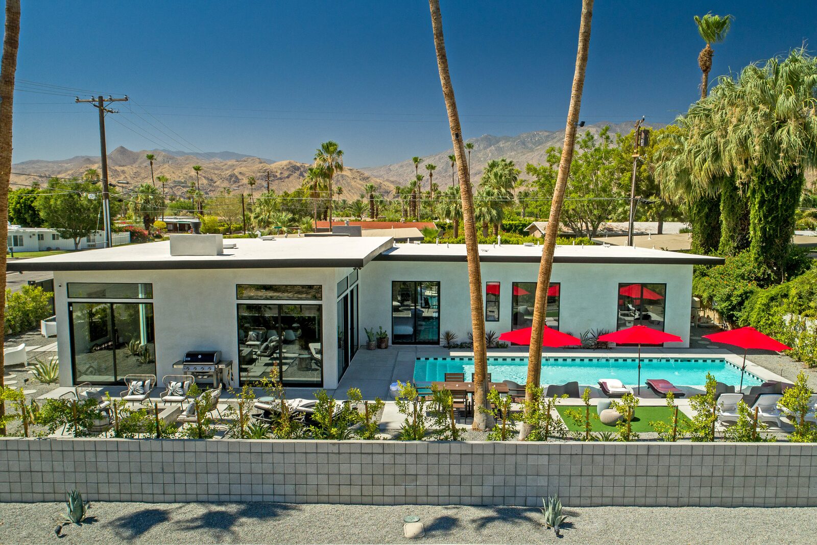 5 Palms Estate poolside daybed with red umbrellas and palms
